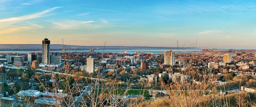 Hamilton downtown skyline with investment properties | Hamilton neighborhood street with residential homes for sale | Real estate investor reviewing Hamilton property documents